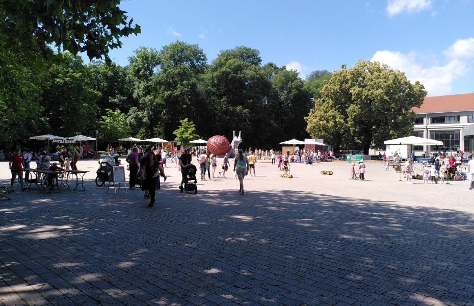 Veranstaltungsplatz draußen - sieht unscharf Personen und Informationsstände - Bäume im Hintergrund