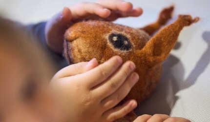 Kinderhände streicheln ein Eichhörnchen aus Stoff