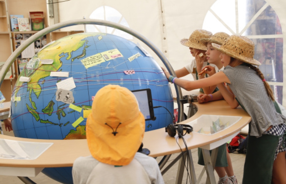 Vier Kinder bekleben eine übergroße Weltkugel