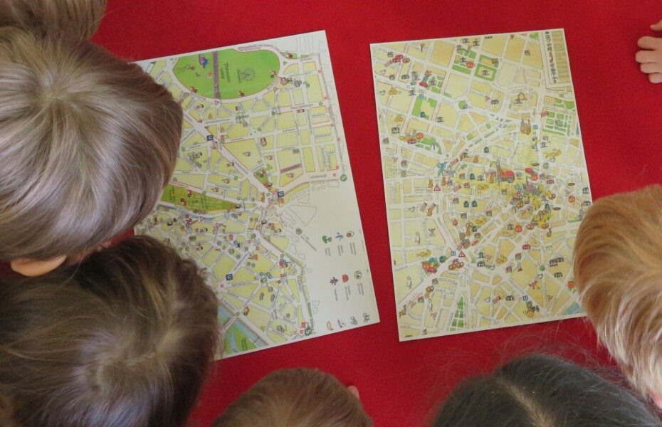 Sicht von oben: fünf Kinderköpfe schauen auf einen für Kinder gestalteten Stadtplan