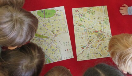 Sicht von oben: fünf Kinderköpfe schauen auf einen für Kinder gestalteten Stadtplan