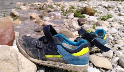 Ein Paar Kinderturnschuhe am Isarufer