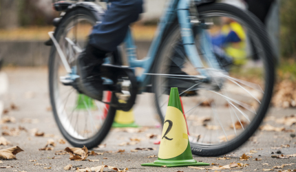 Ein Kind auf einem Fahrrad, von dem nur die Beine zu sehen sind, fährt um kleine Hindernisse