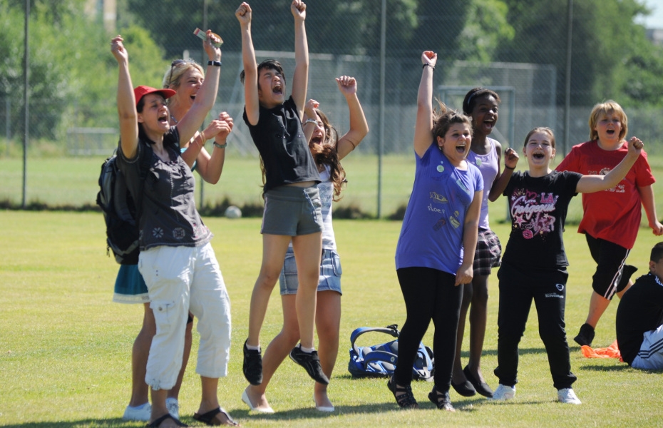 Jugendliche auf einem Sportplatzrasen- sie strecken die Arme in die Luft und freuen sich 